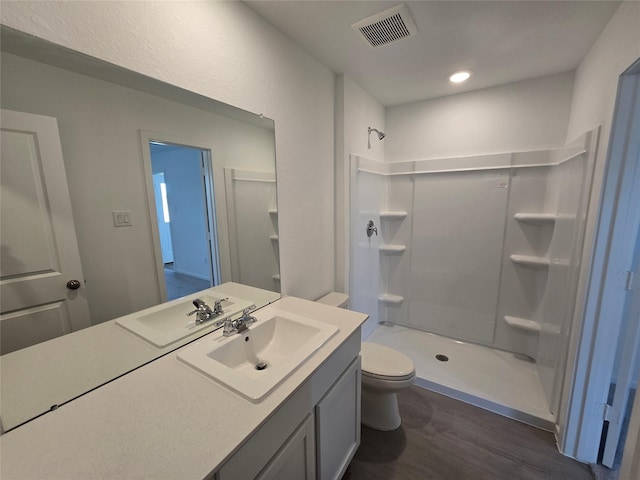 bathroom with toilet, wood finished floors, visible vents, and a stall shower