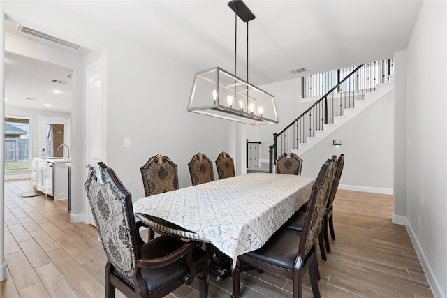 dining space with baseboards, visible vents, stairway, and light wood finished floors
