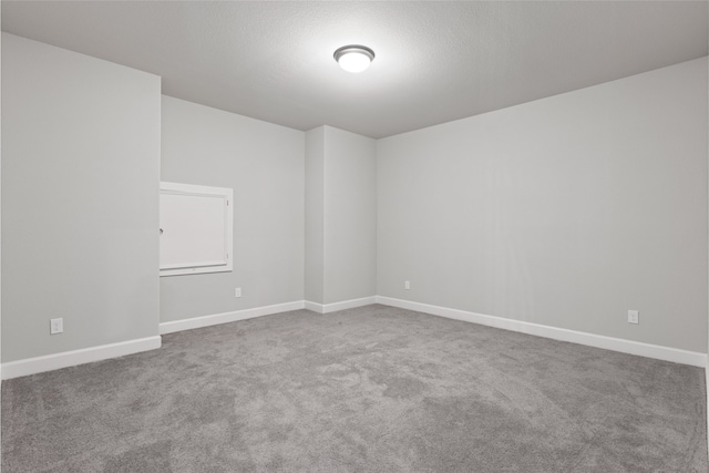 carpeted spare room featuring baseboards