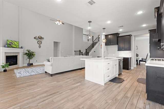 kitchen featuring light wood finished floors, a tile fireplace, visible vents, light countertops, and open floor plan
