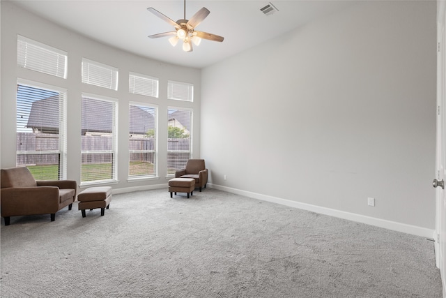 living area featuring baseboards, visible vents, a ceiling fan, and carpet flooring