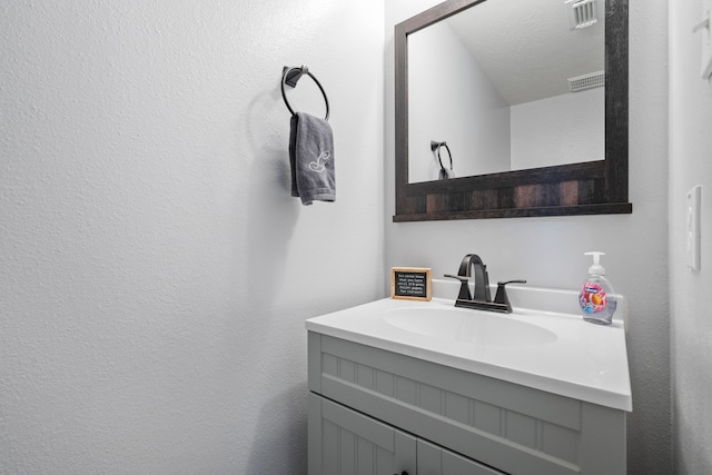 bathroom featuring vanity, a textured wall, and visible vents