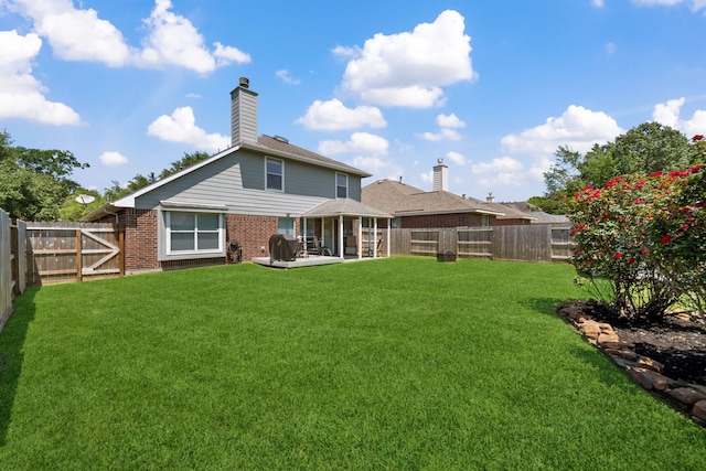 back of house featuring a yard, brick siding, a fenced backyard, and a patio