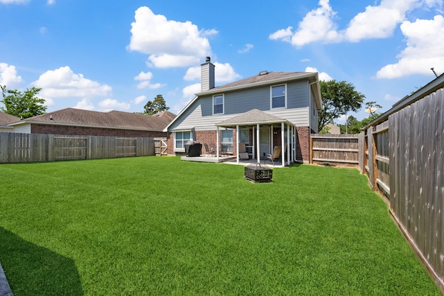 back of property featuring a chimney, a patio, brick siding, and a fenced backyard