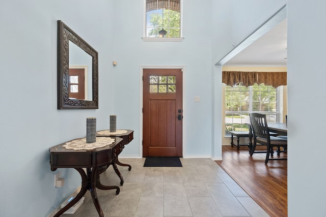 entryway with light tile patterned floors, baseboards, and a high ceiling