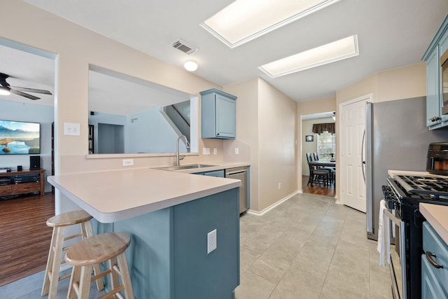 kitchen featuring a breakfast bar, a sink, visible vents, appliances with stainless steel finishes, and blue cabinetry