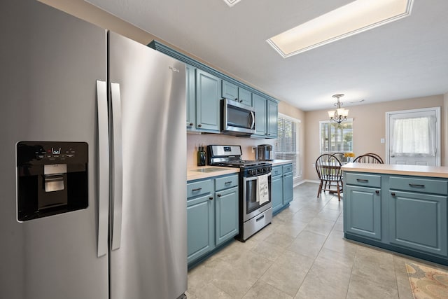 kitchen with pendant lighting, light countertops, blue cabinetry, a notable chandelier, and appliances with stainless steel finishes