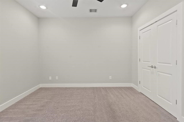 empty room with a ceiling fan, visible vents, light carpet, and baseboards
