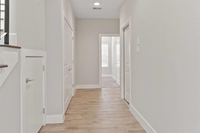 hallway featuring baseboards, visible vents, light wood finished floors, and recessed lighting