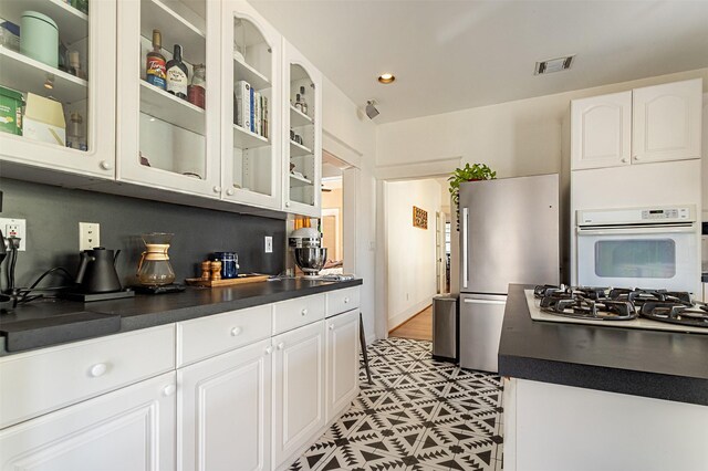 528 Hawthorne St, Houston, TX 77006 - kitchen featuring dark countertops, visible vents, white appliances, and white cabinetry