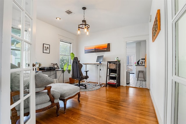 528 Hawthorne St, Houston, TX 77006 - living area with an inviting chandelier, wood finished floors, visible vents, and baseboards