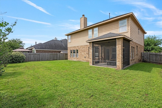 rear view of house featuring a fenced backyard, a yard, brick siding, and a sunroom