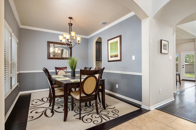 dining space with visible vents, baseboards, an inviting chandelier, arched walkways, and ornamental molding