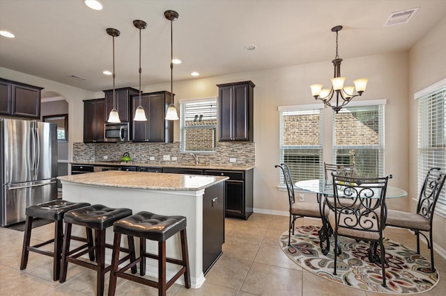kitchen featuring tasteful backsplash, a chandelier, appliances with stainless steel finishes, a kitchen island, and visible vents