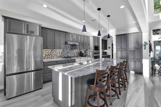 461 Pine Forest Acres Dr, Trinity, TX 75862 - kitchen with tasteful backsplash, gray cabinets, light stone counters, stainless steel appliances, and under cabinet range hood