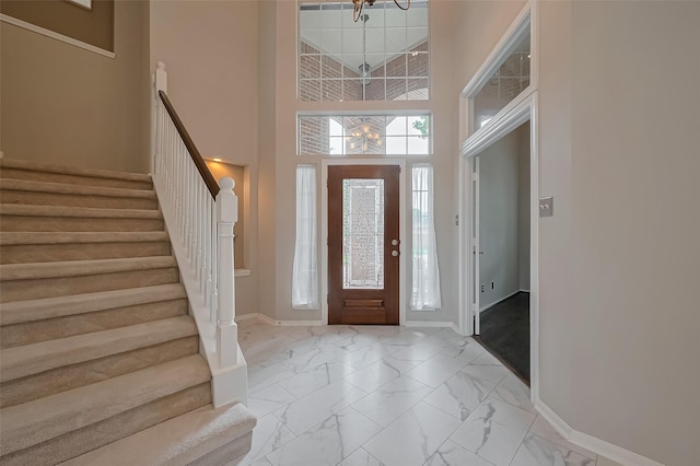 entrance foyer with marble finish floor, stairway, and baseboards