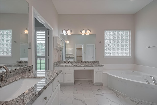 full bathroom featuring two vanities, a bath, marble finish floor, and a sink
