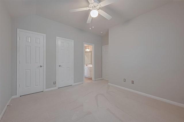 unfurnished bedroom featuring light carpet, ensuite bath, vaulted ceiling, and baseboards