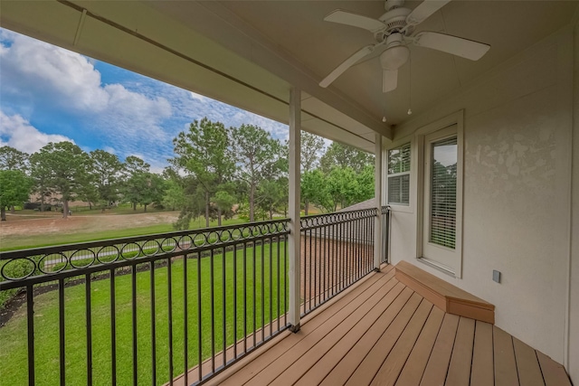 wooden terrace with a ceiling fan and a lawn