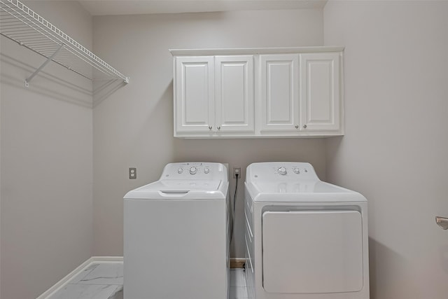 laundry room featuring baseboards, cabinet space, washer and clothes dryer, and marble finish floor