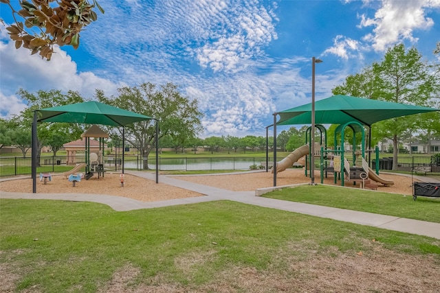 community playground with a lawn, a water view, and fence