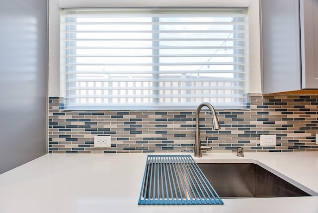interior details with tasteful backsplash, light countertops, and a sink