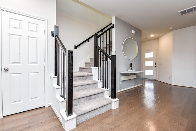foyer featuring recessed lighting, stairway, visible vents, baseboards, and wood finished floors