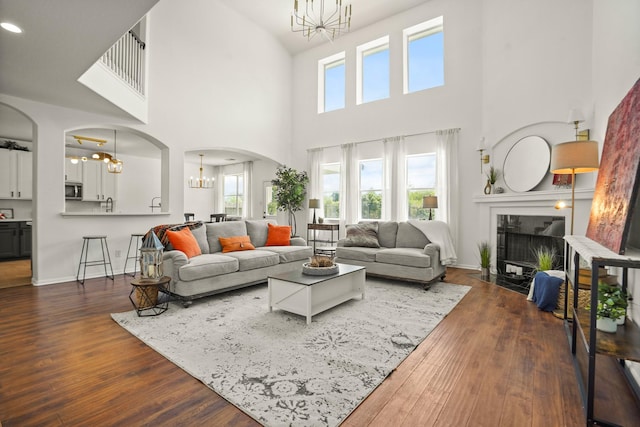 3631 Belmont Shore Ln, Missouri City, TX 77459 - living room featuring a chandelier, arched walkways, a towering ceiling, dark wood-type flooring, and healthy amount of natural light