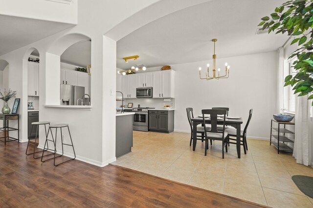 3631 Belmont Shore Ln, Missouri City, TX 77459 - dining room featuring a chandelier, light wood-style floors, arched walkways, and baseboards