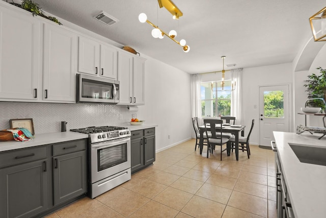 3631 Belmont Shore Ln, Missouri City, TX 77459 - kitchen with appliances with stainless steel finishes, decorative backsplash, light countertops, light tile patterned flooring, and decorative light fixtures