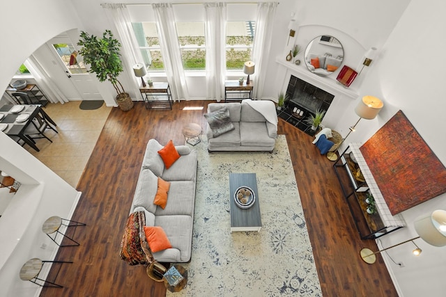 3631 Belmont Shore Ln, Missouri City, TX 77459 - living room featuring arched walkways, wood finished floors, and a tiled fireplace