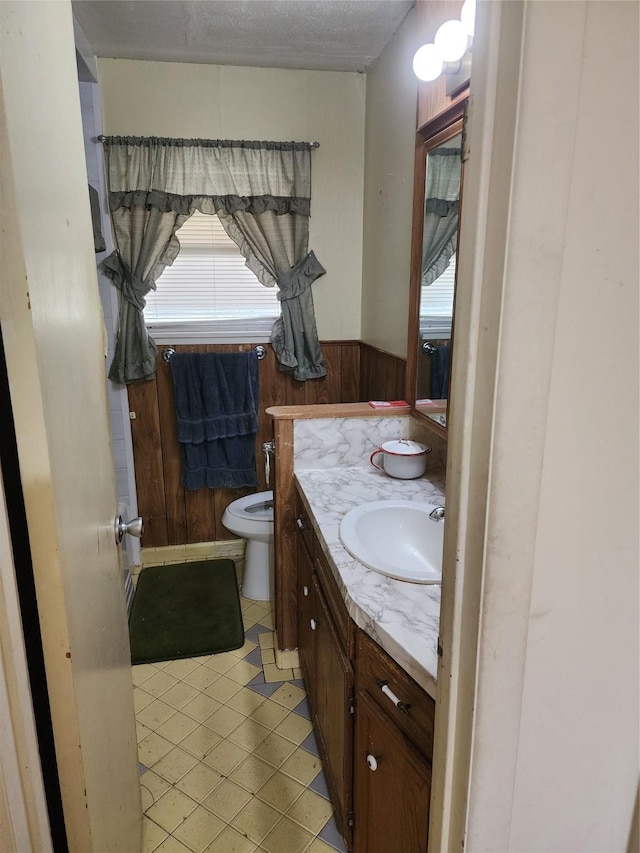918 Redondo Dr, Houston, TX 77015 - half bathroom with wooden walls, a wainscoted wall, vanity, toilet, and tile patterned flooring