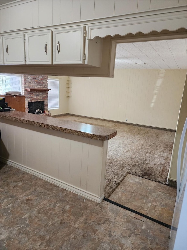 918 Redondo Dr, Houston, TX 77015 - kitchen featuring wood walls, a fireplace, and white cabinets