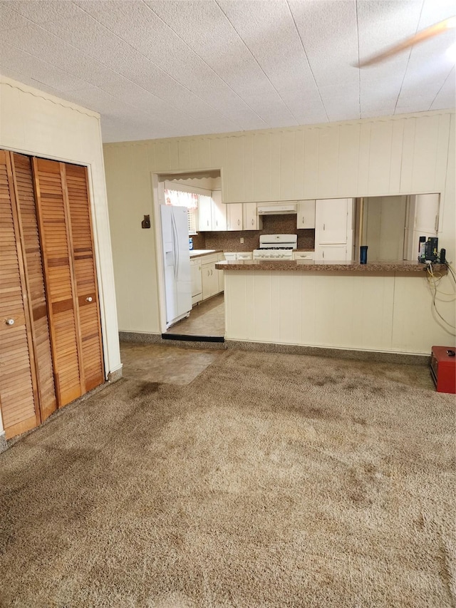 918 Redondo Dr, Houston, TX 77015 - kitchen with white appliances, white cabinetry, carpet flooring, under cabinet range hood, and a peninsula