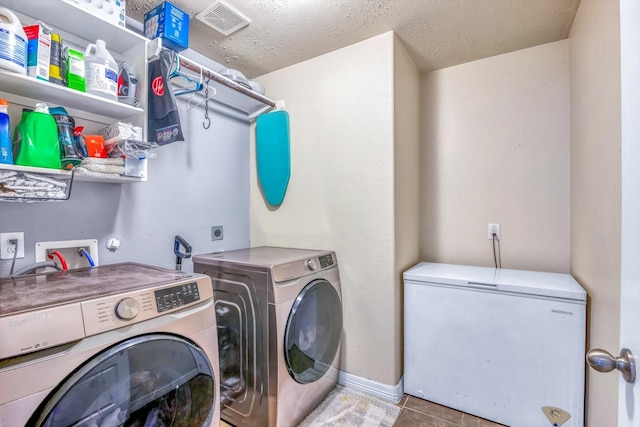 washroom with a textured ceiling, independent washer and dryer, visible vents, baseboards, and laundry area