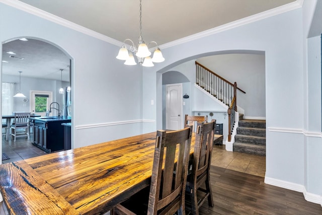 dining area featuring dark wood-style floors, an inviting chandelier, stairs, ornamental molding, and arched walkways