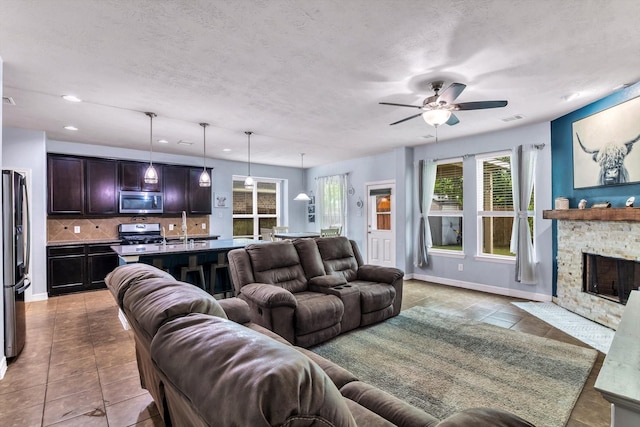 tiled living area featuring recessed lighting, ceiling fan, a fireplace, a sink, and visible vents