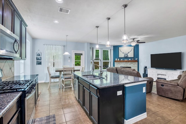 kitchen with appliances with stainless steel finishes, ceiling fan, a fireplace, a sink, and visible vents
