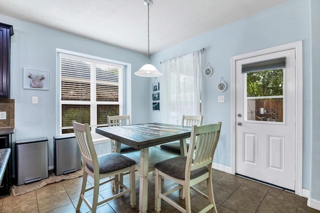 dining area featuring a wealth of natural light, dark tile patterned flooring, and baseboards