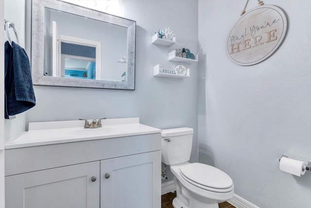 half bathroom with toilet, vanity, and baseboards