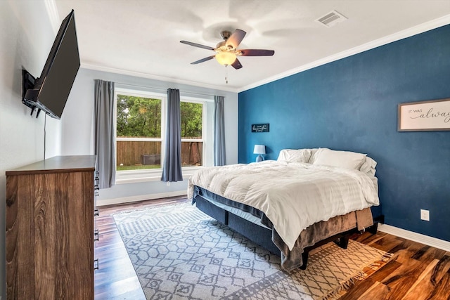 bedroom with visible vents, wood finished floors, ornamental molding, and baseboards