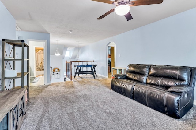 living room with baseboards, arched walkways, a ceiling fan, and carpet flooring
