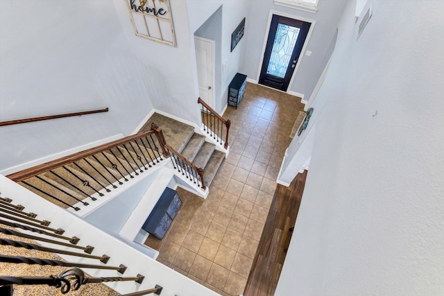 foyer entrance with baseboards, stairway, and tile patterned flooring