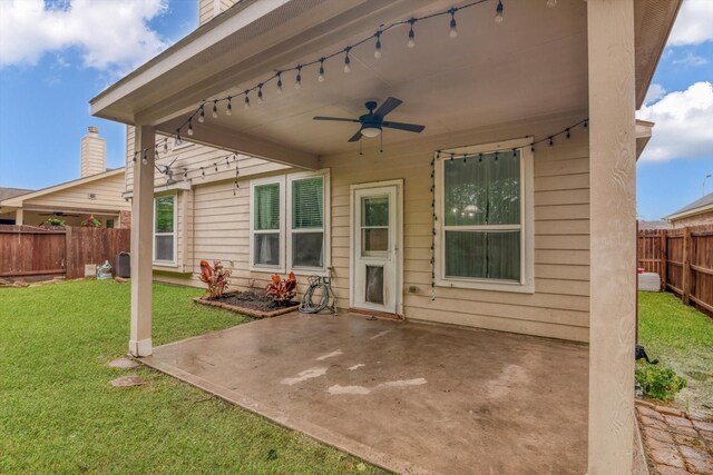back of property with a fenced backyard, a ceiling fan, a yard, and a patio area