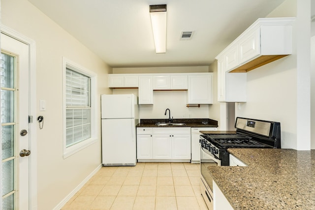 kitchen with a sink, visible vents, white cabinetry, freestanding refrigerator, and gas range