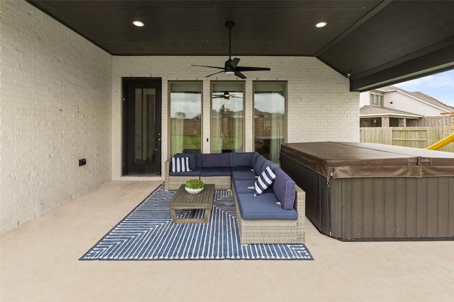 view of patio featuring a ceiling fan, a hot tub, fence, and an outdoor hangout area