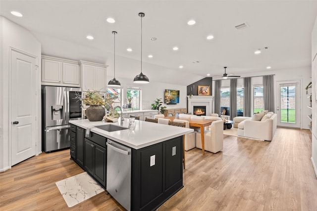 kitchen with a lit fireplace, recessed lighting, dark cabinetry, a sink, and stainless steel appliances