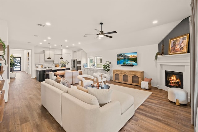 living room featuring a large fireplace, a ceiling fan, wood finished floors, and a wealth of natural light