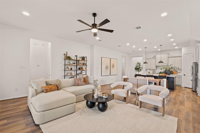 living area with a ceiling fan, recessed lighting, wood finished floors, and visible vents