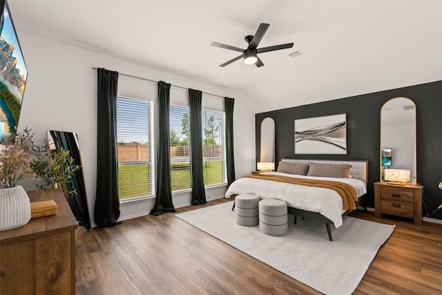 bedroom featuring ceiling fan, visible vents, arched walkways, wood finished floors, and lofted ceiling